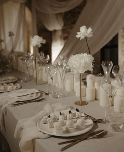 Prise de vue d'une table des mariés tout en blanc remplie de bougies de fleurs et avec des assiettes d'antipastis blancs servies