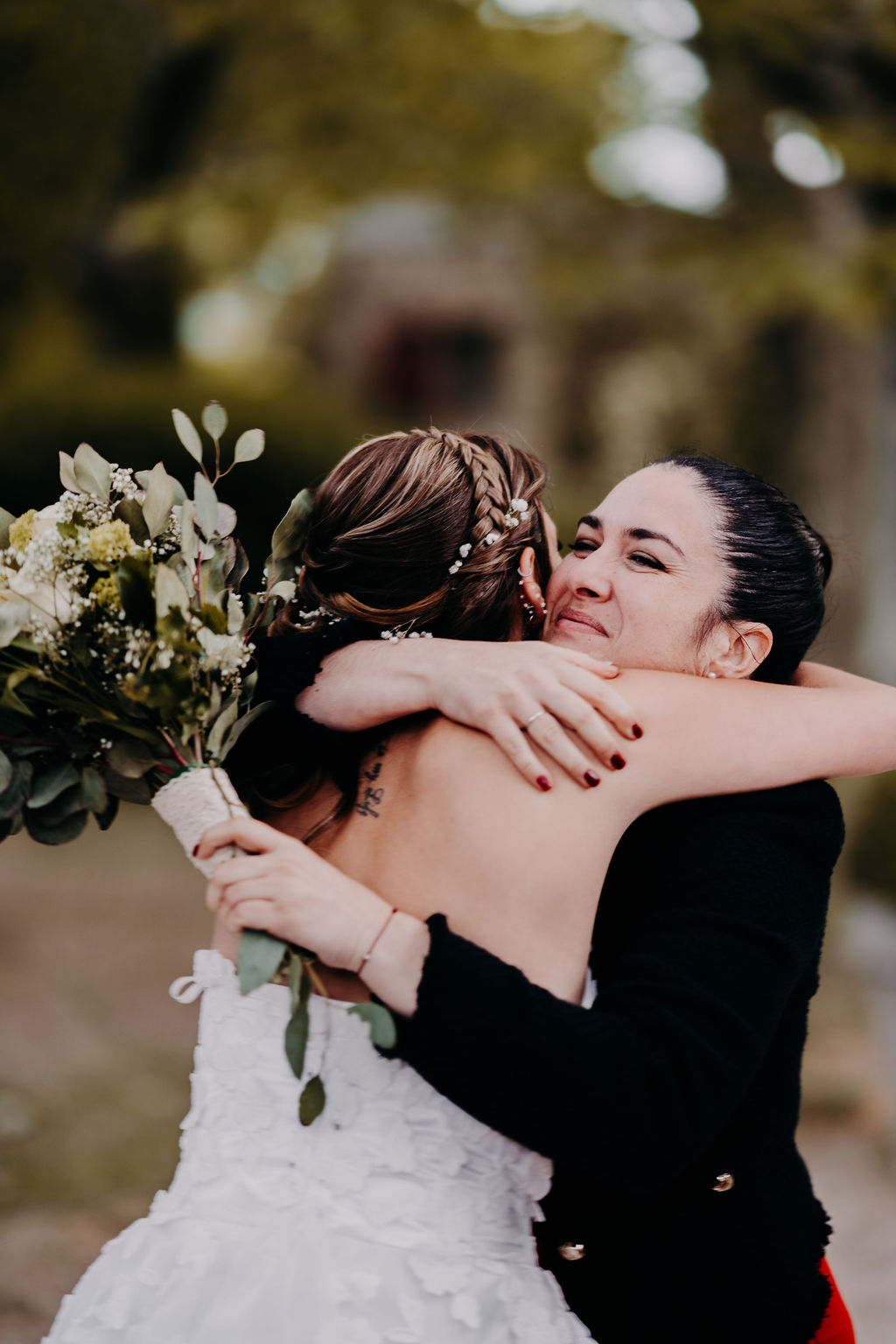 plan resseré sur la mariée et l'invitée qui a attrapé le bouquet, enlacée